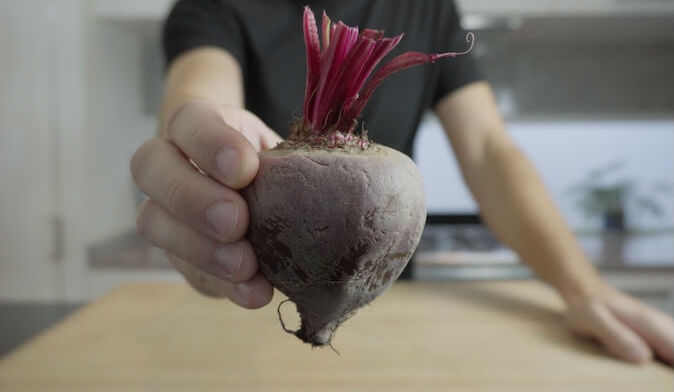 hand holding whole raw beetroot