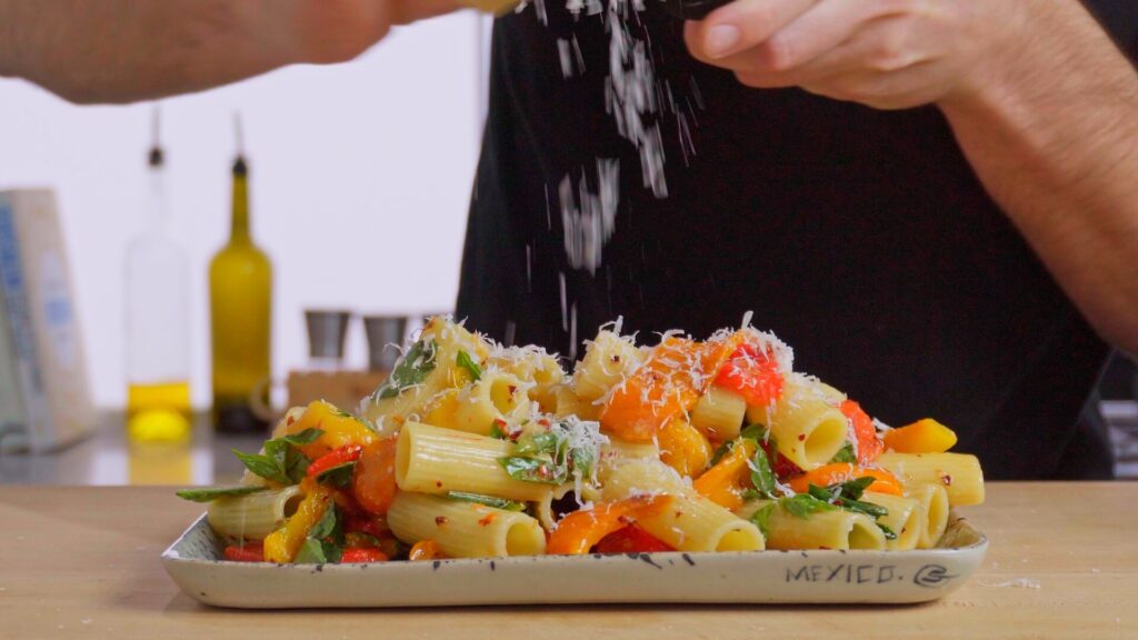 plate of pasta salad with parmesan cheese being grated over