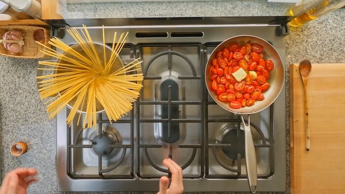 spaghetti being cooked in salted water on a stove top