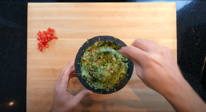 guacamole being made in a molcajete