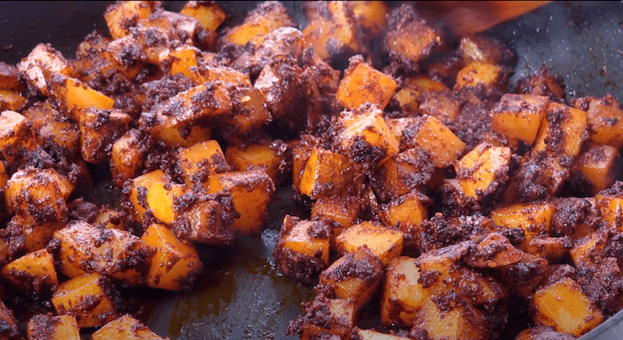 potatoes being fried in a spice paste