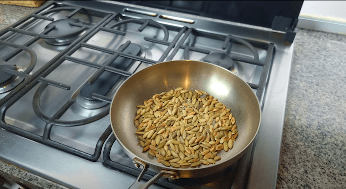 pumpkin seeds being toasted in a pan