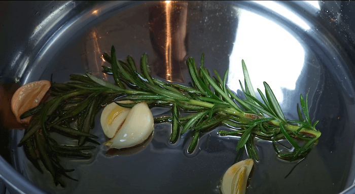 rosemary and garlic being cooked in olive oil