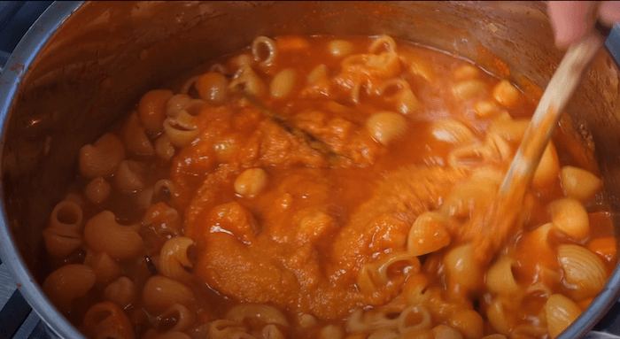 pasta being cooked in a tomato-based sauce