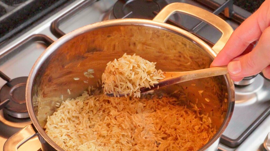 wooden spoon holding toasted rice showing the colour