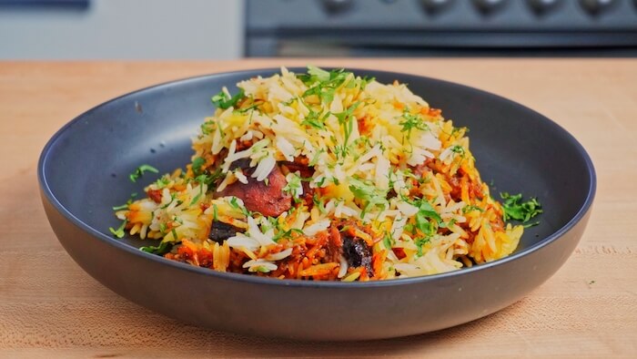 Bowl of cooked rice and chicken with herbs and spices