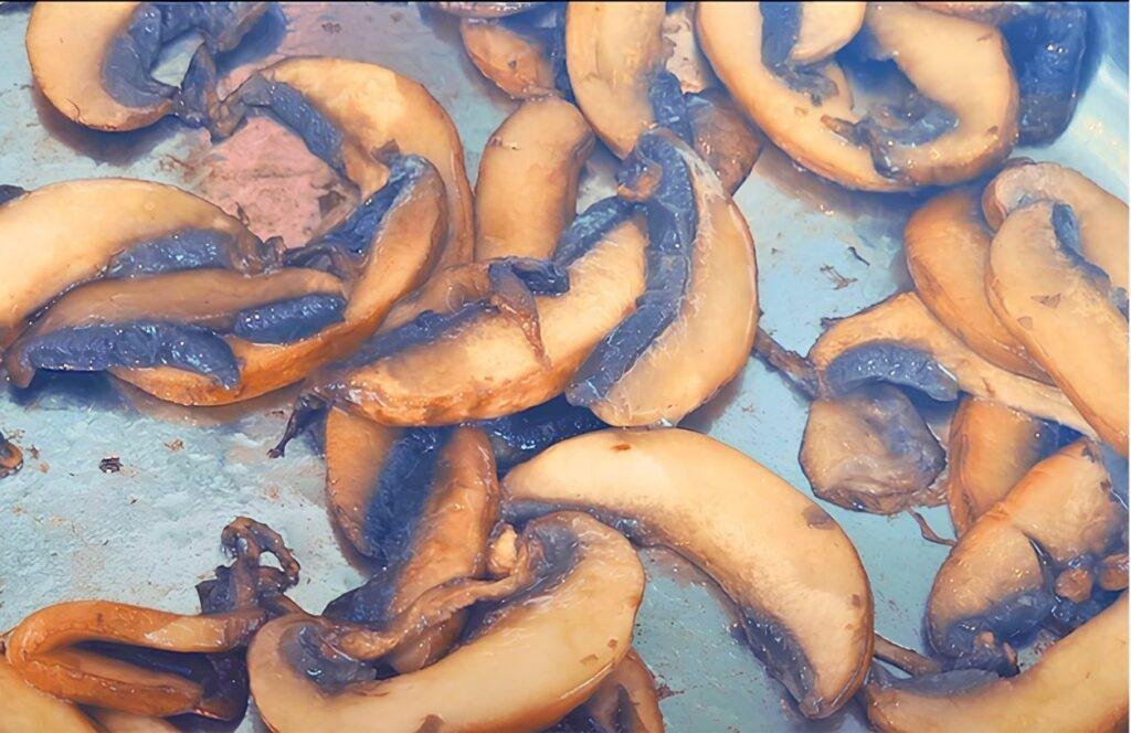 Close up of sliced mushrooms browning in a pan