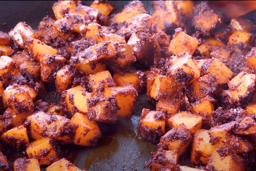 Potatoes being fried in a spiced paste.