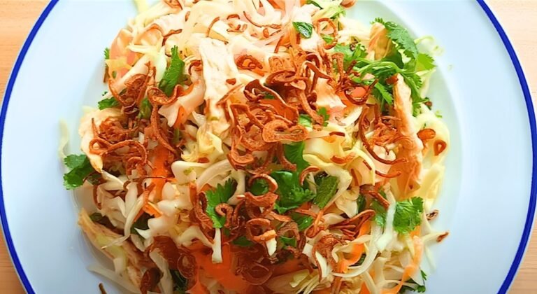 close up of Vietnamese chicken salad with crispy fried shallots and coriander on a white plate with a blue rim