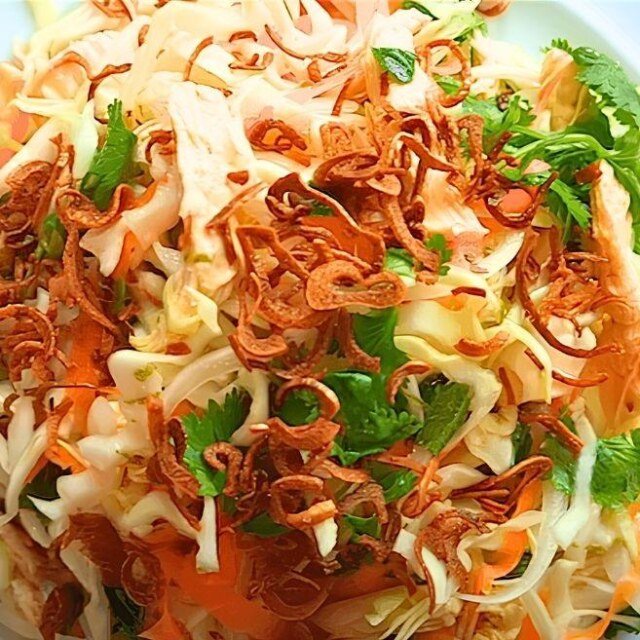 close up of Vietnamese chicken salad with crispy fried shallots and coriander on a white plate with a blue rim