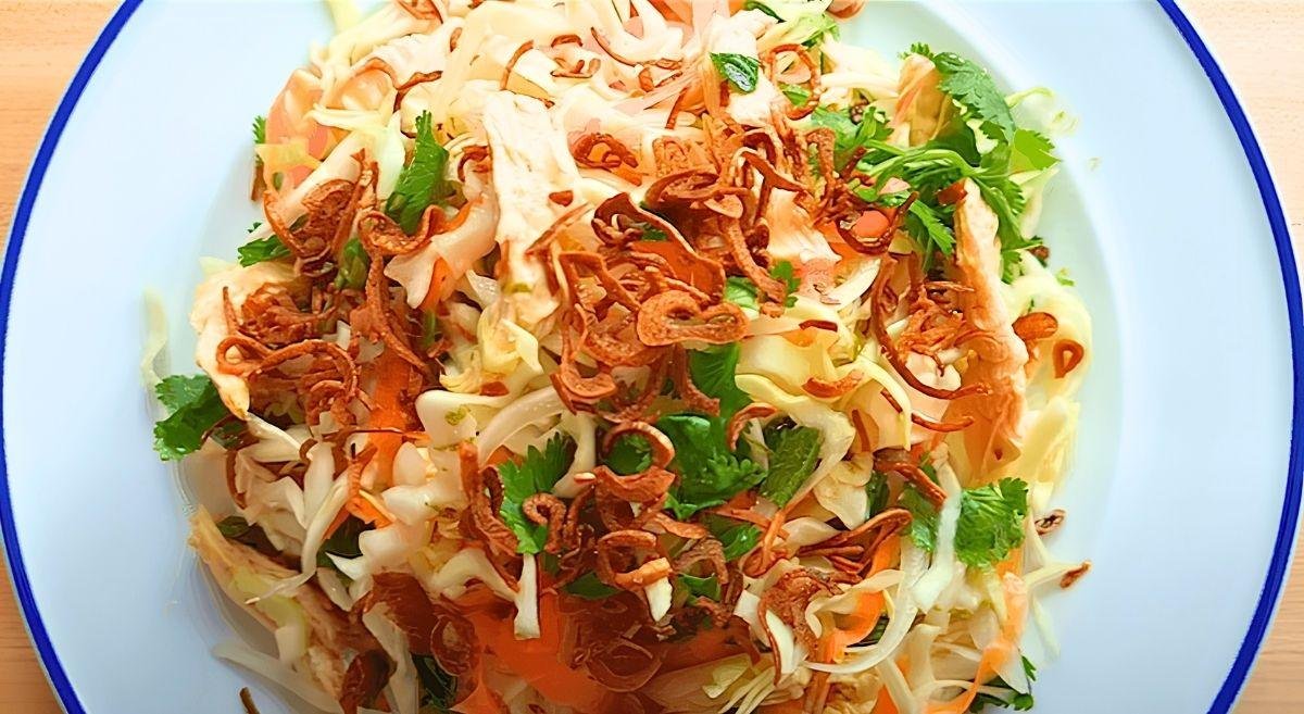 close up of Vietnamese chicken salad with crispy fried shallots and coriander on a white plate with a blue rim