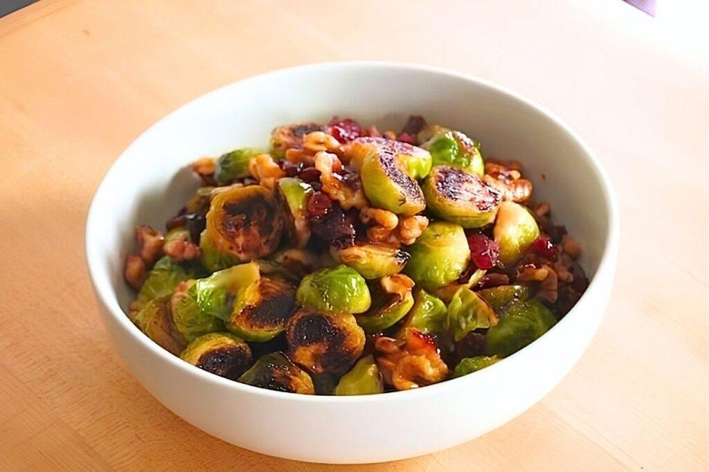 Close up of charred brussels sprouts with walnuts and dried cranberries in a white bowl