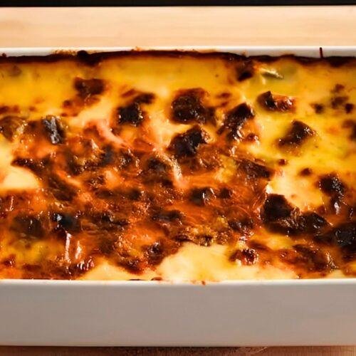 Overhead close up of golden leek gratin with a browned crust in a white baking dish