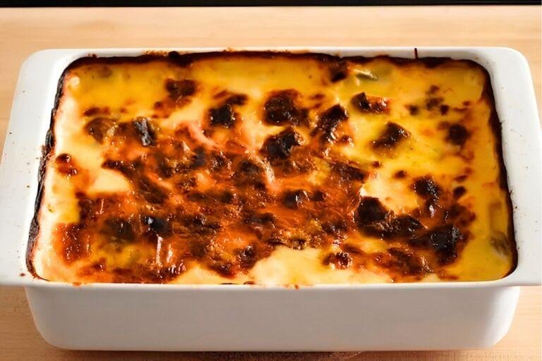 Overhead close up of golden leek gratin with a browned crust in a white baking dish