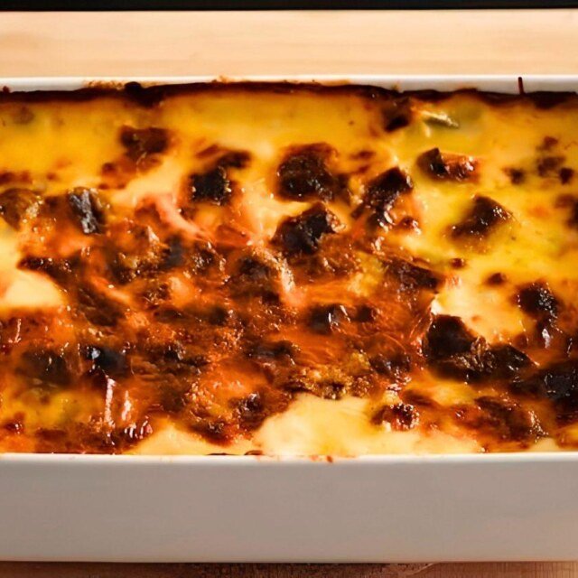 Overhead close up of golden leek gratin with a browned crust in a white baking dish