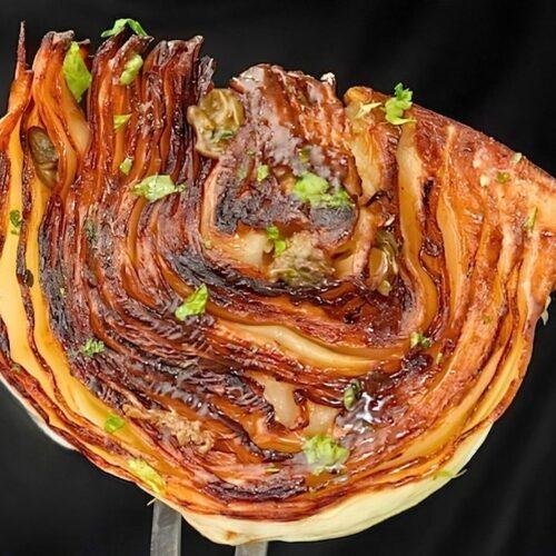 fork holding up caramelised piece of pan roasted cabbage