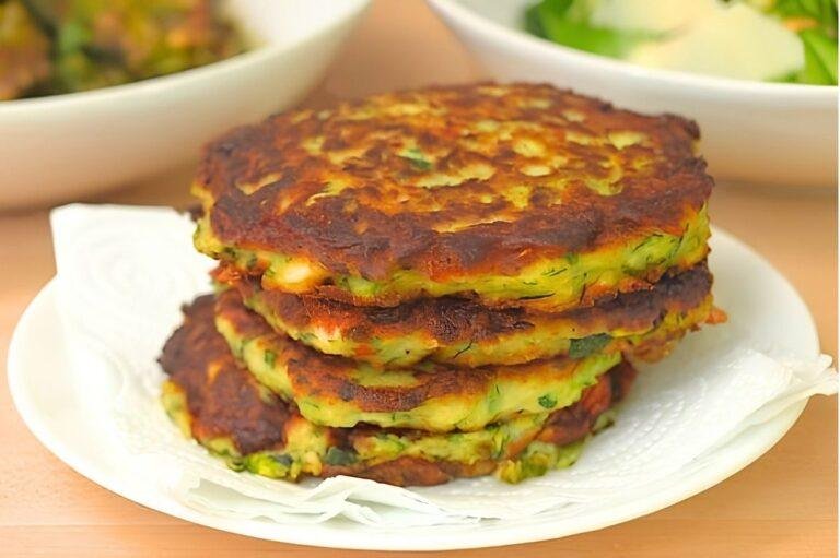 Stack of golden courgette fritters on a plate lined with paper towel