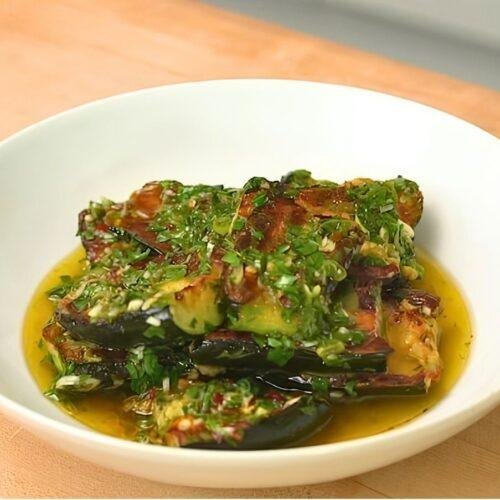 Charred courgettes topped with chimichurri in a shallow white bowl