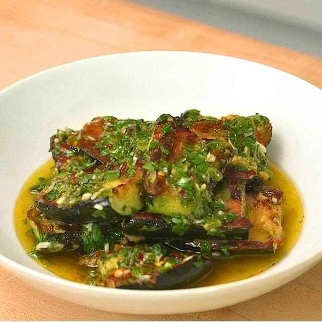 Charred courgettes topped with chimichurri in a shallow white bowl