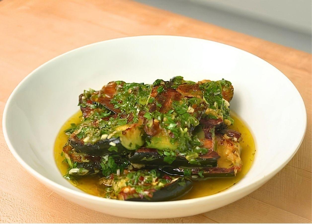 Charred courgettes topped with chimichurri in a shallow white bowl