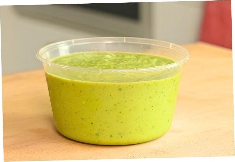 Tub of creamy green avocado salsa on a wooden counter