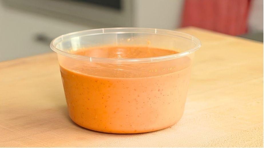 Tub of creamy spicy peanut salsa on a wooden counter