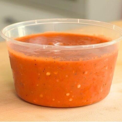 Tub of homemade red tomato salsa on a wooden counter