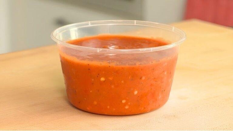 Tub of homemade red tomato salsa on a wooden counter