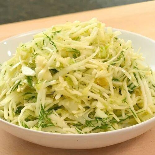 White bowl of shredded cabbage slaw with dill