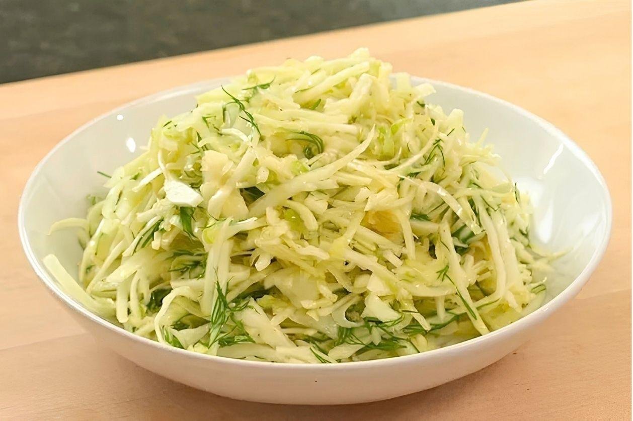 White bowl of shredded cabbage slaw with dill