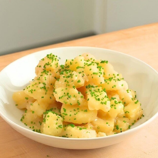 A white bowl of Swabian potato salad on a worktop.