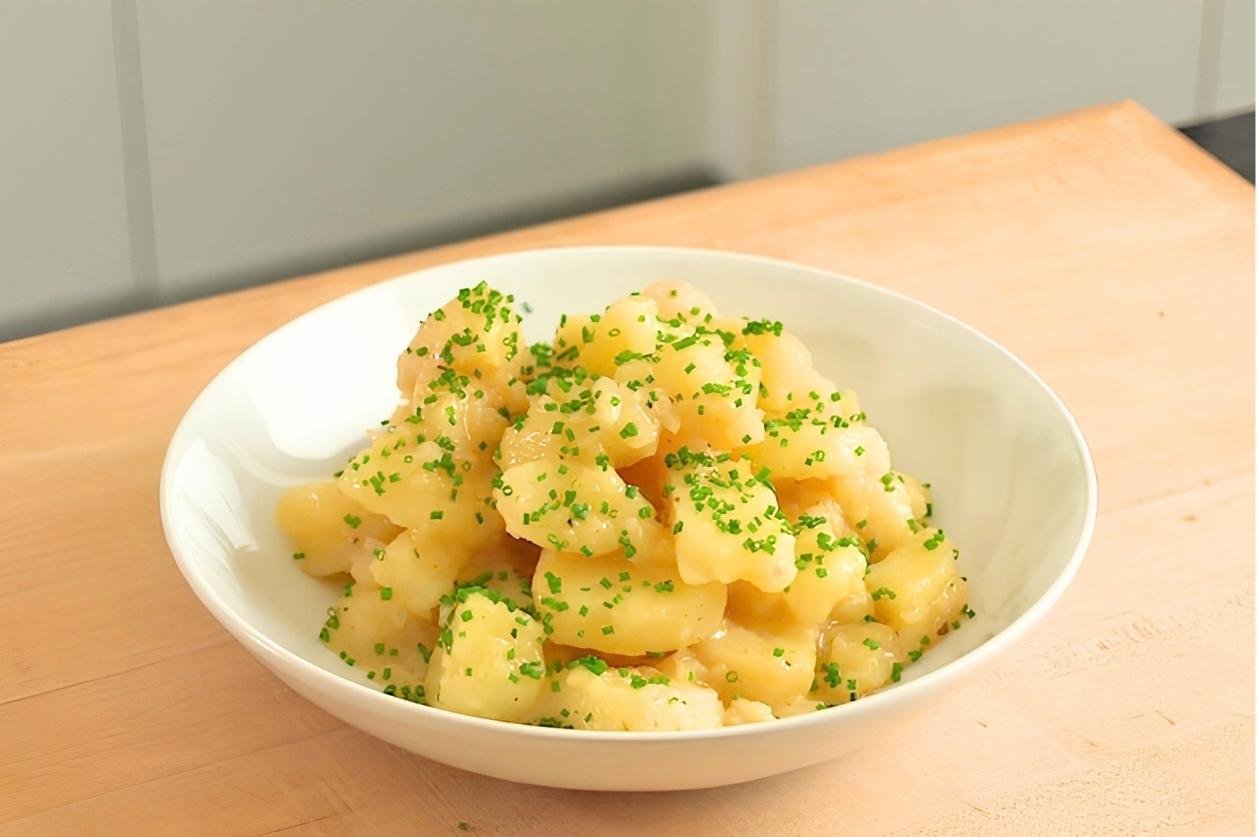 A white bowl of Swabian potato salad on a worktop.