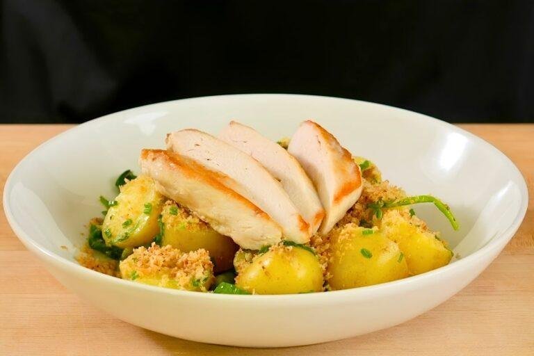 pan seared chicken breast on top of new potatoes, spinach and peas with a dressing