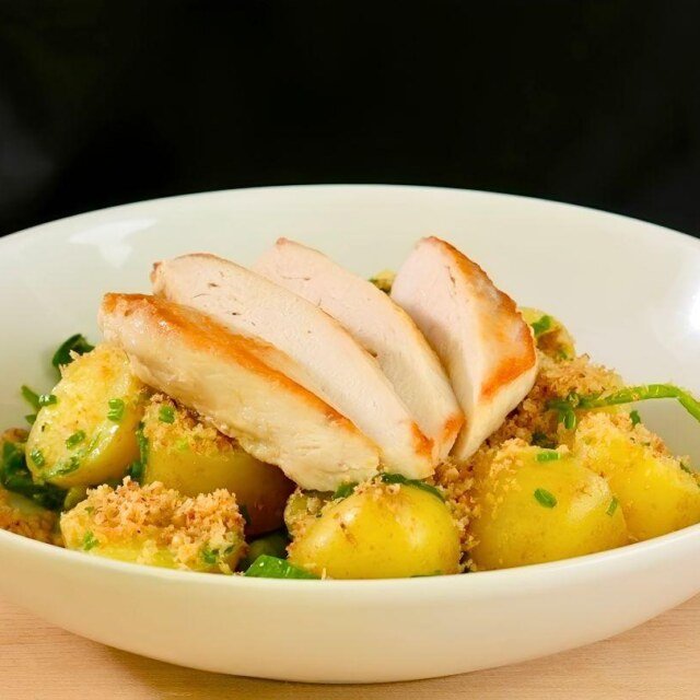 pan seared chicken breast on top of new potatoes, spinach and peas with a dressing