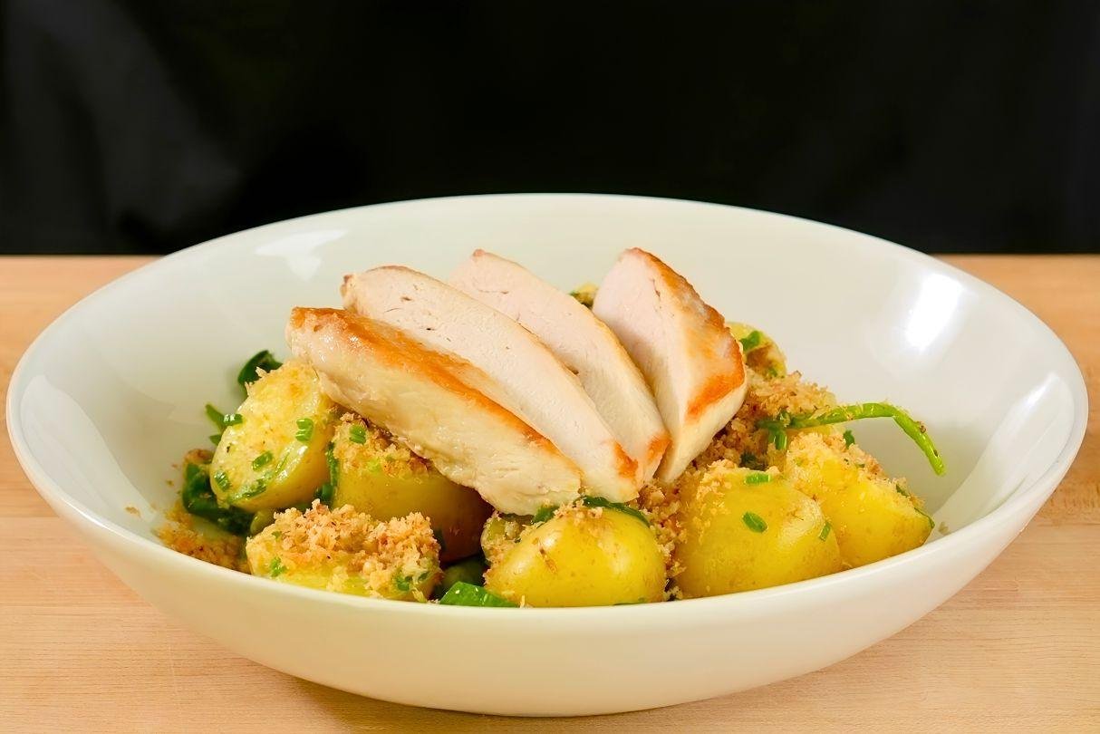 pan seared chicken breast on top of new potatoes, spinach and peas with a dressing