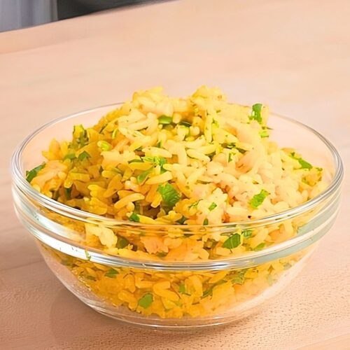 yellow rice in a bowl on wooden surface
