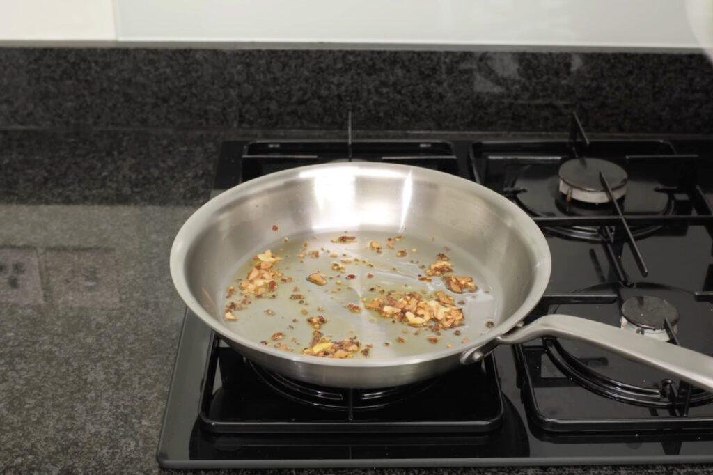 Fried garlic and aromatics browning in a steel pan on a gas hob