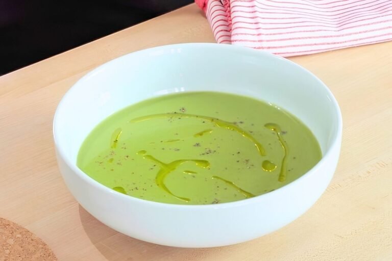 Bowl of smooth green asparagus soup drizzled with olive oil and black pepper