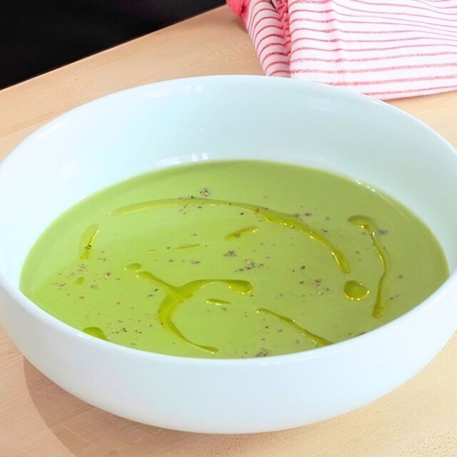 Bowl of smooth green asparagus soup drizzled with olive oil and black pepper