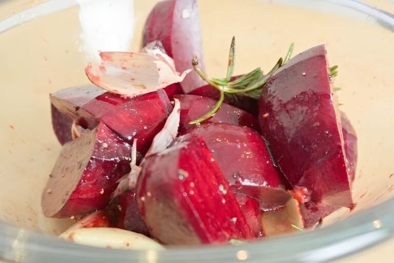 Close up of chopped beetroot with rosemary, garlic and salt in a glass bowl