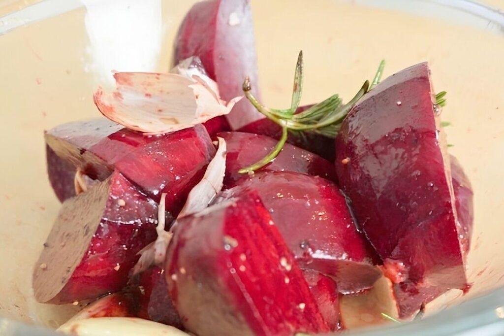 Close up of chopped beetroot with rosemary, garlic and salt in a glass bowl
