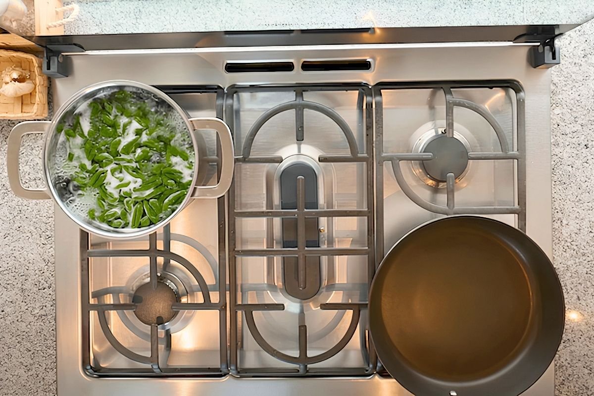 Spinach cavatelli boiling in a steel pot on the hob beside a pan of olive oil