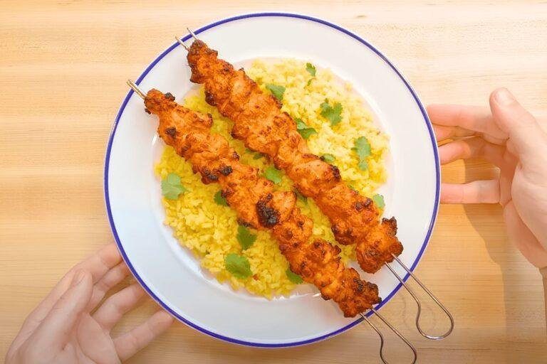 Chicken tikka skewers served on rice on a plate