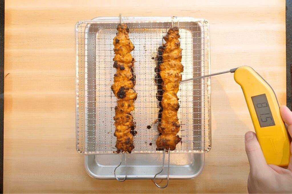 Thermometer checking the temperature of the chicken tikka skewers
