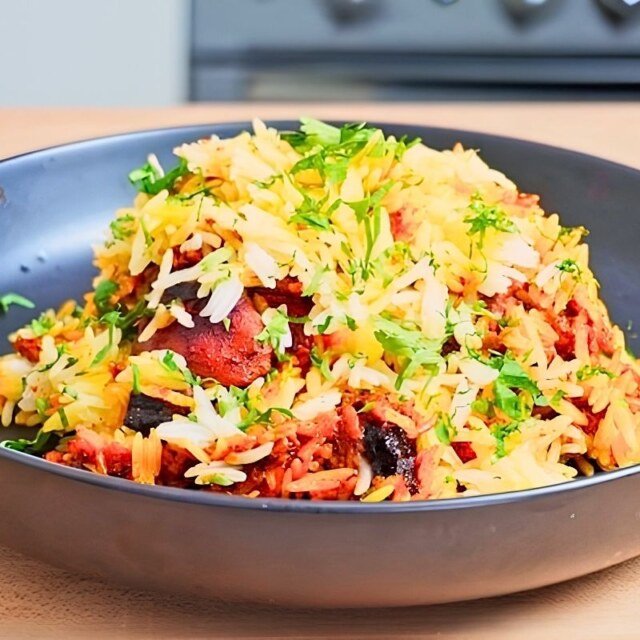 Bowl of cooked rice and chicken with herbs and spices