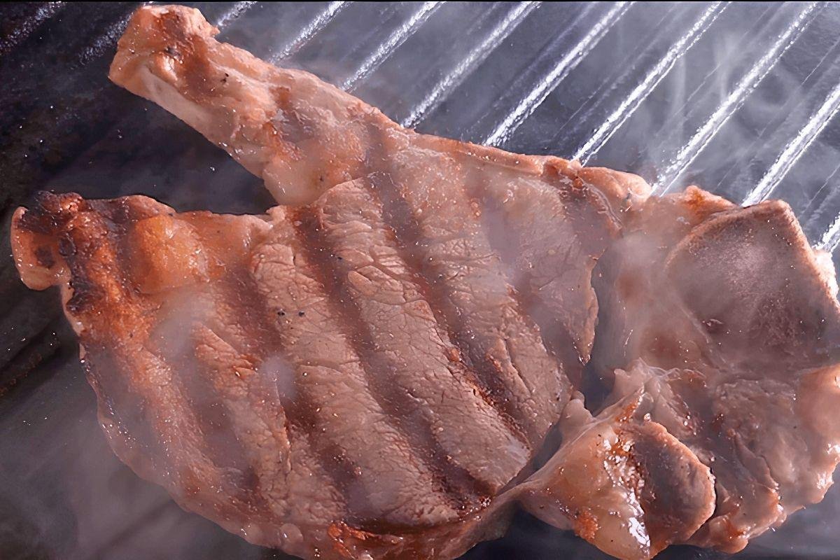 Seared pork chop with grill marks on a ridged grill pan, steaming