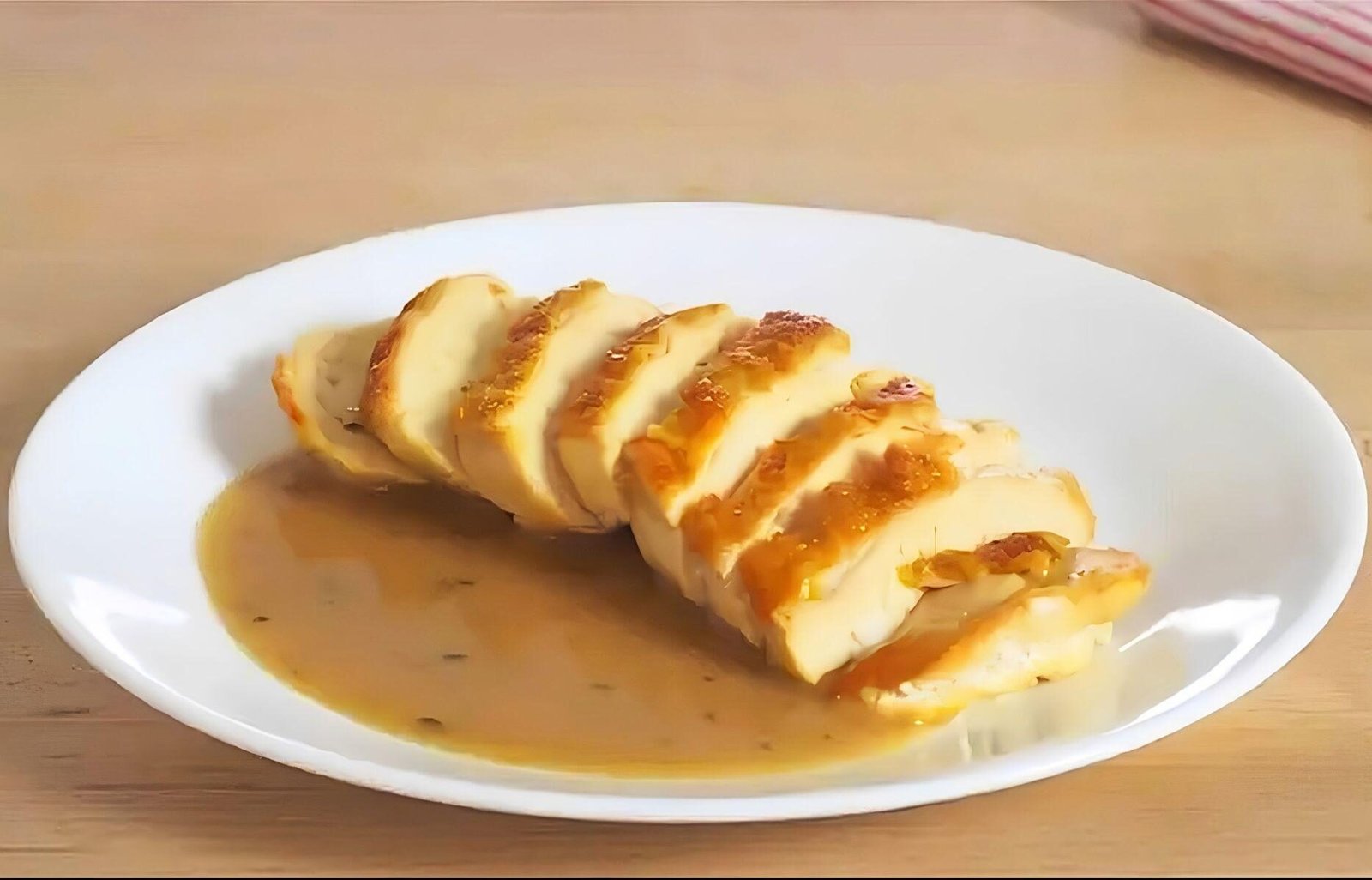 plate with sliced chicken breast and a chicken pan sauce