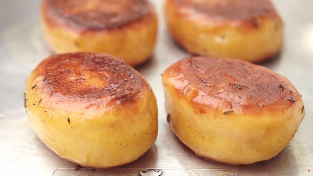 Close up of golden fondant potatoes with browned tops on a lined tray