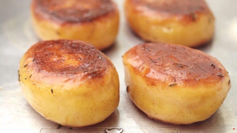 Close up of golden fondant potatoes with browned tops on a lined tray