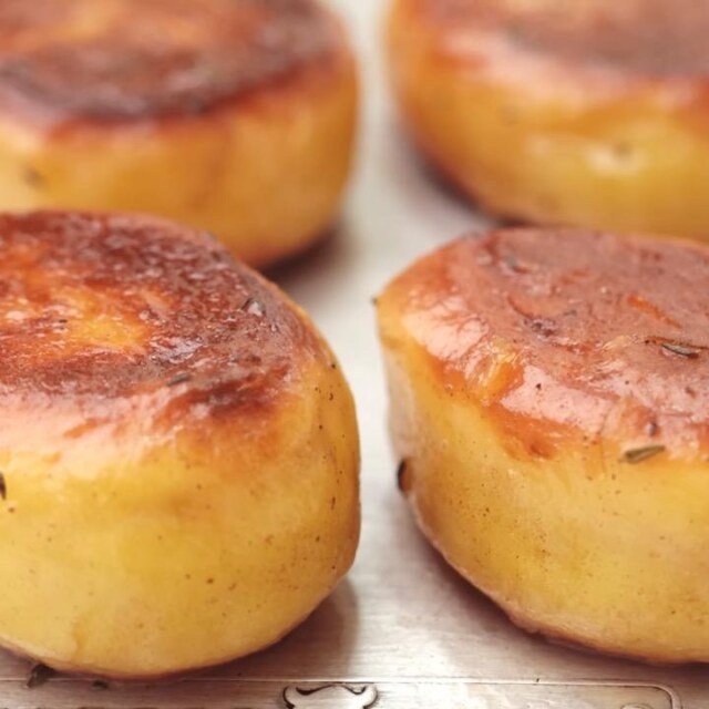 Close up of golden fondant potatoes with browned tops on a lined tray